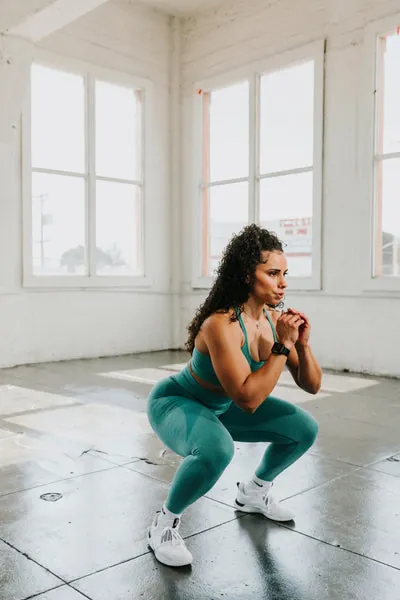 Woman doing squats in a sunlit studio